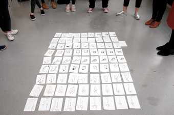 81 small pencil drawings arranged on the floor in a grid