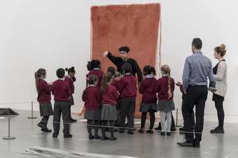 A group of children looking at an artwork with an artist