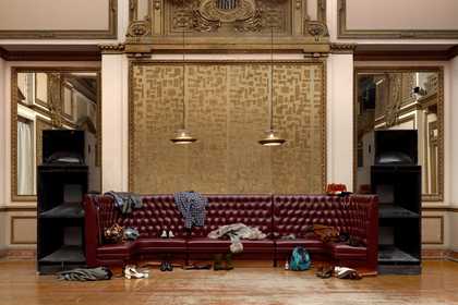 empty room with a big red leather sofa with items on it 