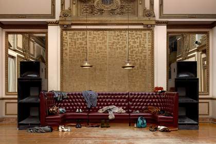 empty room with a big red leather sofa with items on it 