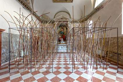 installation view of lots of branches standing up in a gallery space