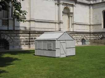 a plaster cast of a shed sits on the lawn in front of Tate Britain