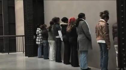 Still image from video footage of Group of persons facing a wall performance