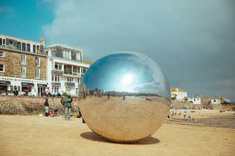 A large silver ball sits on the sand of St Ives' Harbour Hotel in the sunshine