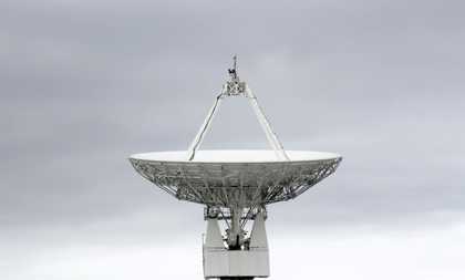 a big satellite dish with a grey cloudy sky behind it