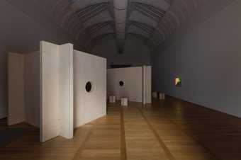 photograph of the exhibition. plywood structures small stools and a film projected onto the wall