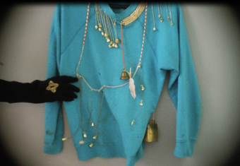 Film still of blue sweater with gold bells and ropes attached