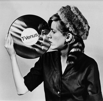 Black and white photograph of a woman looking at her reflection in a vinyl record