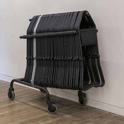 A stack of foldable stools next to the gallery wall.