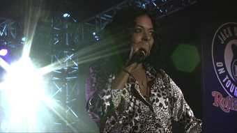 Film still of woman singing into a microphone