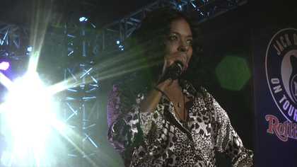 Film still of woman singing into a microphone