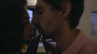 Colour film still of a man and woman embracing about to engage in a kiss