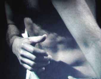 A man's hand covering his bare torso 