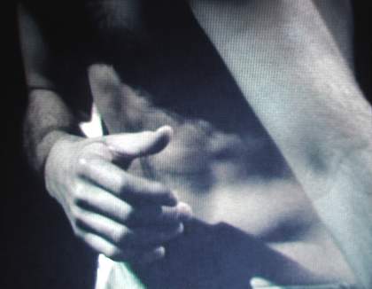 A man's hand covering his bare torso
