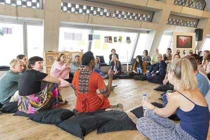 Photograph of participants in a workshop in Tate Exchange at Tate Modern, sitting in a circle on the floor