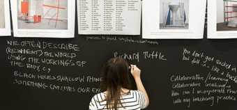 Woman writing on a blackboard about ideas around exhibitions as part of a summer school project