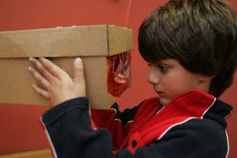 Kid looking into the sunset box he has made