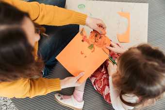 A young girl and her mother cut out a figure they've drawn on paper