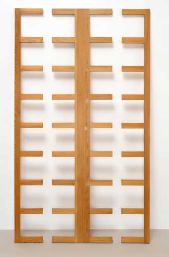 Sculpture made of pine standing upright against a wall, a wooden slatted framework