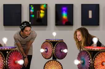 Two people looking at an installation with light bulbs in it