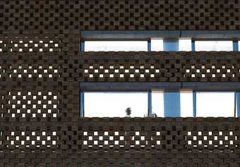 Detail of the perforated brickwork design and the horizontal windows on the new building