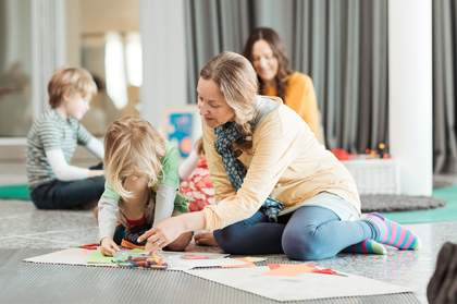 A mother and her young son sit on the floor making art together