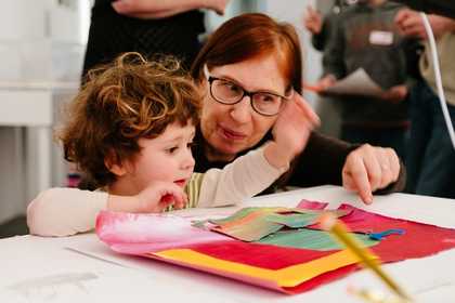 Children talk whilst holding paint brushes