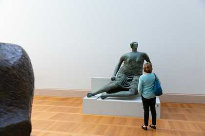 a woman stands in front of a Henry Moore sculpture