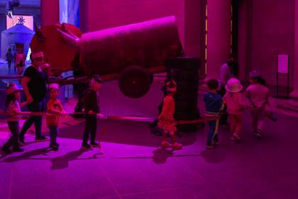 An early years group walk through the Heather Philipson commission wearing crowns