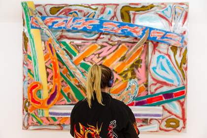 Visitor looking at a colourful abstract painting by Frank Stella in the Constellation display at Tate Liverpool