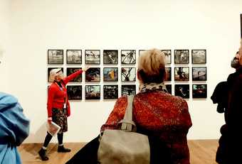 a guide points at a series of photographic works in Tate Modern