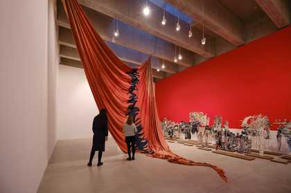 large red sail hanging from ceiling in gallery space