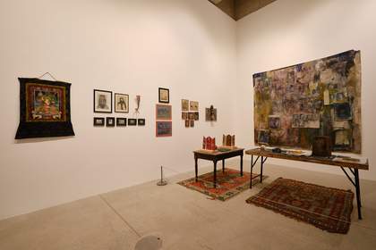 works hanging on gallery walls and a table covered in objects