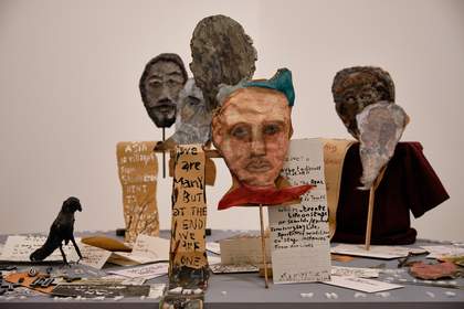 a group of cut-out heads arranged on a table