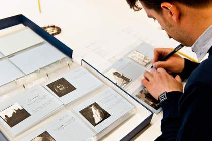 Tate Britain preservation volunteer Aurelio re-numbering Keith Piper photographs