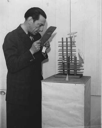 Paul Nash examining his sculpture Moon Aviary through a blue glass screen which gave a 'moonlight effect' for the viewer