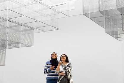 two visitors looking up at installation art