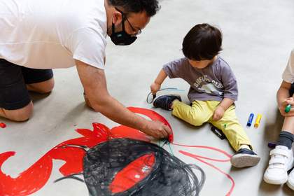 A boy and his father draw on the floor with red pens