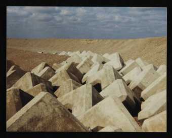 Film Still from Prunella Clough film showing her Colour Photograph of Sea Defenses
