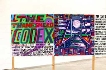 a colourful long painting stands on wooden slats the first panel says 'the thamesmead codex'