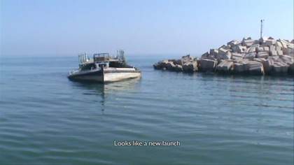 Photograph of a small boat sinking off of a coastline