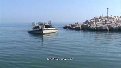 Photograph of a small boat sinking off of a coastline