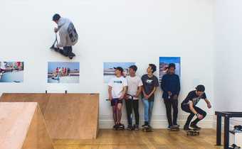 Young boys skateboard beside artworks