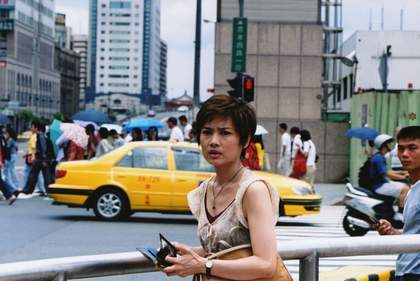 a person walks across a street with a taxi in the background