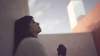 Film still of a woman sitting in profile with the sky behind 