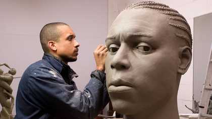 Thomas J Price carving a sculpture out of clay