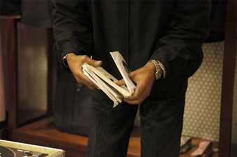 photograph showing the lower half of a man in a suit holding vinyl records