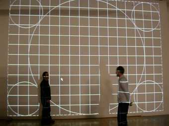 Two people stand in front of a projected wall