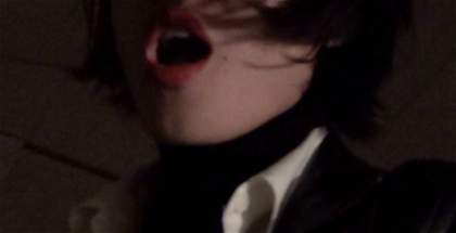 Out-of-focus photograph of one performers' faces in a dark environment