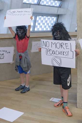 two young people wearing guerrilla masks holding up signs